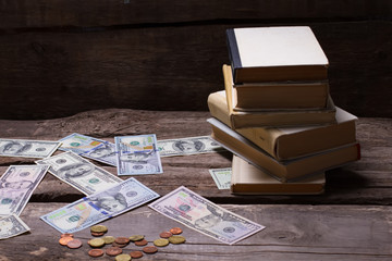 Old books and money on a vintage wooden background.