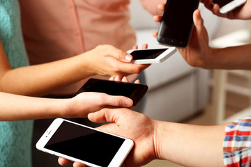 Many hands holding mobile phones close up