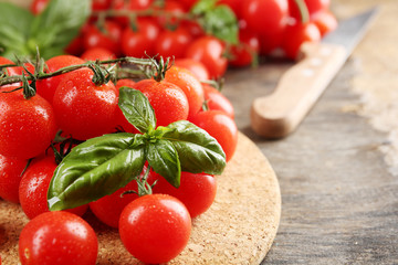 Cherry tomatoes with basil on wooden table close up