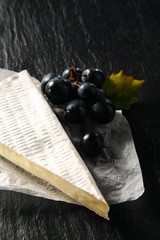 Cow's Milk Cheese Wedge and Grapes on a Paper