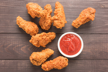 fried chicken drumstick and ketchup on wooden background