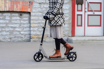 Girl in casual wear on kick scooter on street