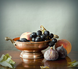 still life, summer fruits in an ancient copper bowl: figs, peaches, grapes.
