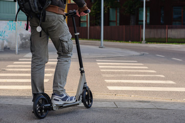 Young man in casual wear on kick scooter on street