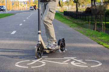 Fototapeta premium Young man in casual wear on kick scooter on street