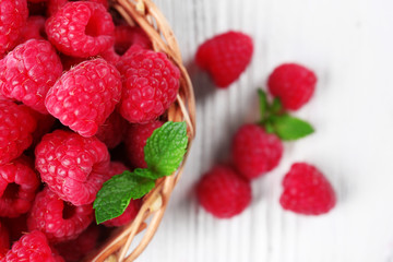Fresh red raspberries in wicker basket on wooden table, top view