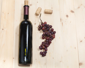 Fototapeta premium Bottle of old wine, sear grape and corks on wooden table