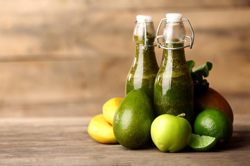 Green healthy juice with fruits and herbs on wooden table close up