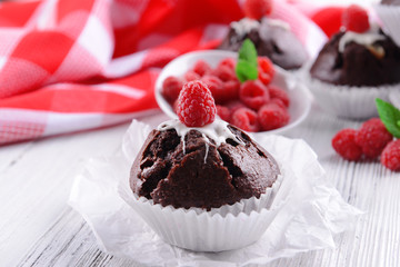 Delicious chocolate cupcakes with berries and fresh mint on table close up