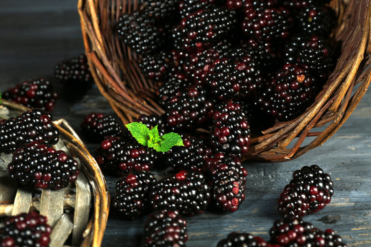 Heap of sweet blackberries with mint in basket on table close up