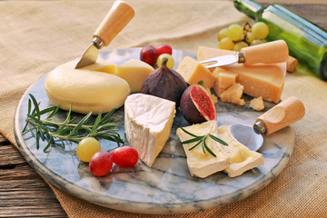 Marble board with various cheese , grapes, figs on sackcloth background 