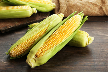 Fresh corn on cobs on wooden table, closeup