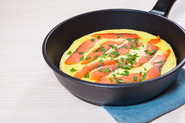 omelet with smoked salmon in a frying pan