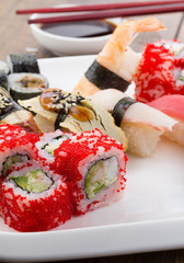 Sushi set on a white plate over vintage wooden background