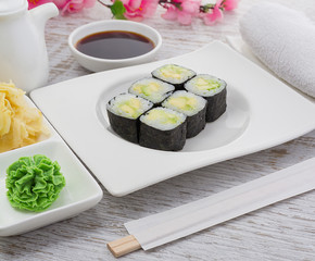 Japanese cuisine. Sushi on a white plate over vintage wooden background.