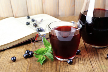 Fresh currant juice with berries and book on table close up