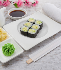 Japanese cuisine. Sushi on a white plate over vintage wooden background.