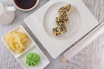 Japanese cuisine. Sushi on a white plate over vintage wooden background.