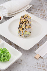 Japanese cuisine. Sushi on a white plate over vintage wooden background.