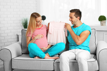 Obraz premium Young pregnant woman with husband on sofa in room
