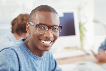 Portrait of happy man wearing eyeglasses while sitting at desk 