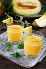 Glasses of melon cocktail on wooden background