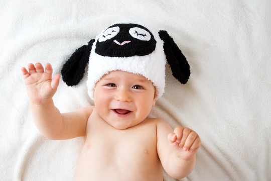 Baby in a sheep hat lying on soft blanket