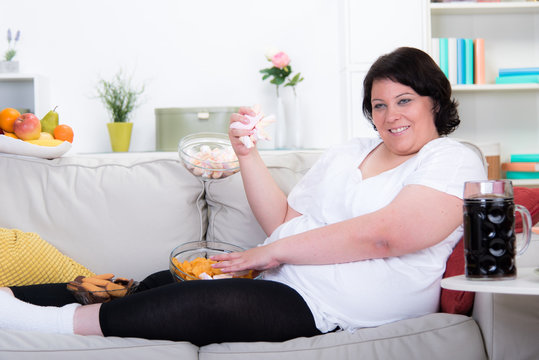 Frau auf dem Sofa isst ungesund