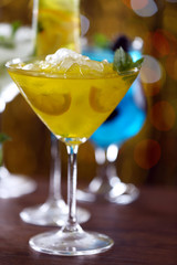 Glasses of cocktails with ice on blurred lights background
