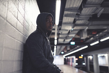 Urban fashion african american man with hoody leaning against wh