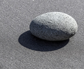 Stone on sand on the bank of Pacific ocean on Kamchatka