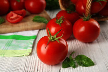 Whole and sliced red tomatoes on cutting board closeup