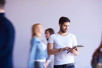 student working on tablet, people group passing by