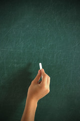 Naklejka premium Female hand writing on blackboard with chalk, close up