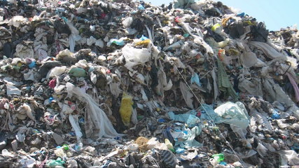 Trash wave. Illegal landfill above fields.