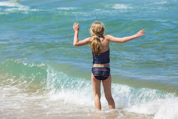 Fototapeta na wymiar Young Girl swims beach shoreline ocean waves 