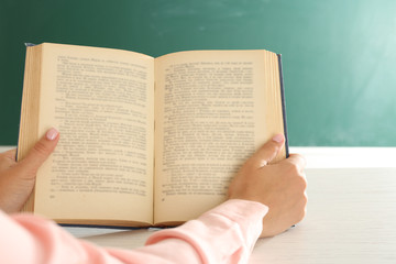 Women hands with book on blackboard background