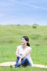 Fototapeta na wymiar 草原に座る若い女性