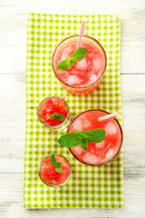 Cold watermelon desserts and drinks in glasses, on wooden table background