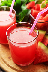Cold watermelon drinks in glasses, on wooden table background