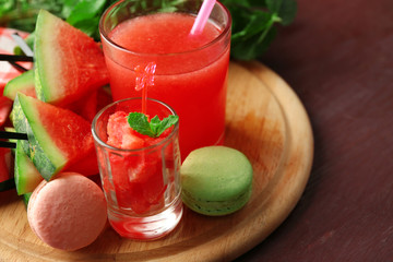 Cold watermelon desserts and drinks in glasses, on wooden table background