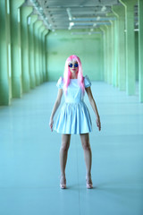 Young woman in mini dress posing like doll inside empty building