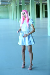Young woman in mini dress posing like doll inside empty building
