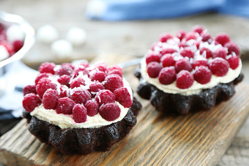 Sweet cakes with raspberries on wooden table background