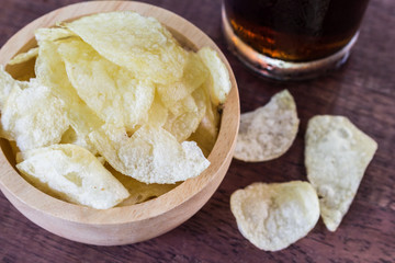 potato chips and cola in glass  on wooden table.