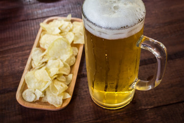beer in glass with snack potato chips  on wooden table