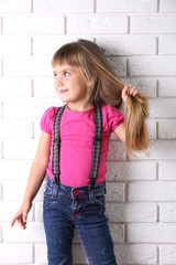 Beautiful little girl on light wall background