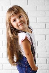 Beautiful little girl on light wall background
