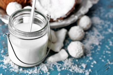 Homemade candies in coconut flakes and ingredients on color wooden background