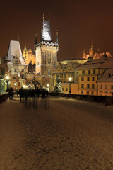 Fototapeta na wymiar Night snowy Prague Bridge Tower and St. Nicholas' Cathedral from Charles Bridge with its Statues, Czech republic